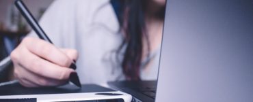 junge frau hinter laptop macht notizen auf tablet, foto: unsplash.com, josefa-ndiaz