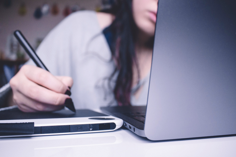 junge frau hinter laptop macht notizen auf tablet, foto: unsplash.com, josefa-ndiaz