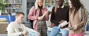 Porträt einer multiethnischen Gruppe von Studenten in der Hochschulbibliothek mit einem Jungen im Rollstuhl im Vordergrund, AdobeStock_Seventyfour