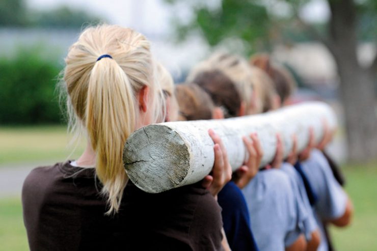 team traegt baumstamm, rueckenansicht, foto: istock, figure8photos