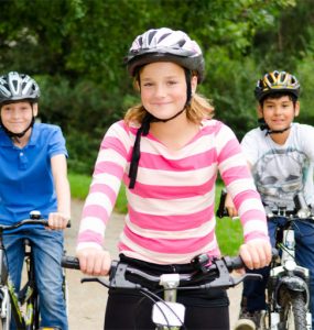 drei kinder auf dem fahrrad mit helm, foto: fotolia, racle fotodesign