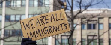 pappschild we are all immigrants vor gebaeude, foto: fotolia, jp photography