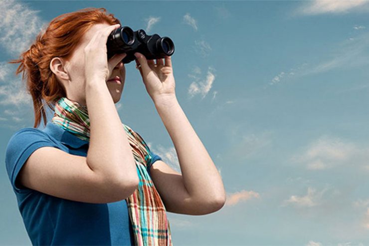 Frau blickt durch ein Fernglas