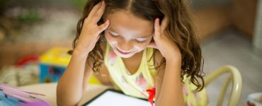 kleines maedchen schaut versonnen auf leuchtendes tablet, foto: unsplash.com, patricia-prudente