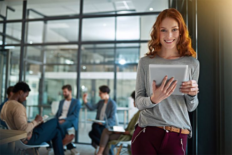 junge frau mit laptop in der hand lehnt an buerotuer, foto: istock, peopleimages