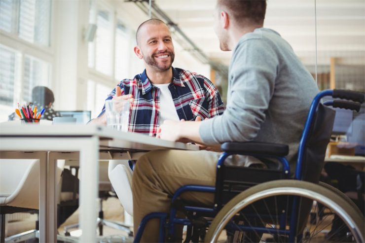 junger mann im rollstuhl im kollegengespraech am tisch, foto: istock, wavebreakmedia