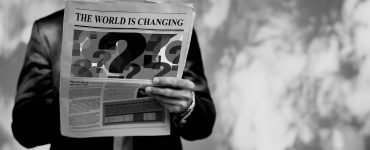Mann hält Zeitung mit Fragezeichen in der Hand