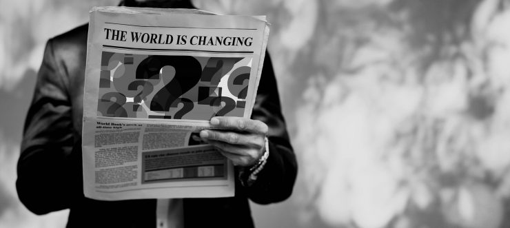 Mann hält Zeitung mit Fragezeichen in der Hand