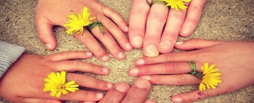 fünf zusammengehaltene Hände mit Blumen