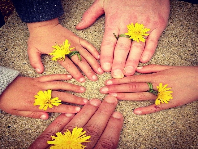 fünf zusammengehaltene Hände mit Blumen