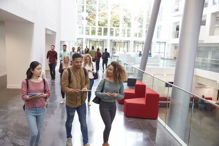 Junge Studierende laufen durch Universitätsgebäude, iStock, monkeybusiness