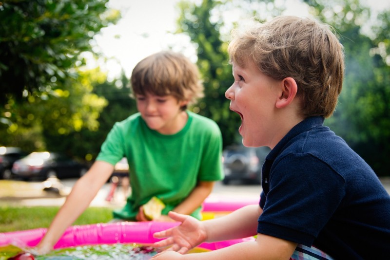 Zwei Kinder spielen draußen mit Wasser