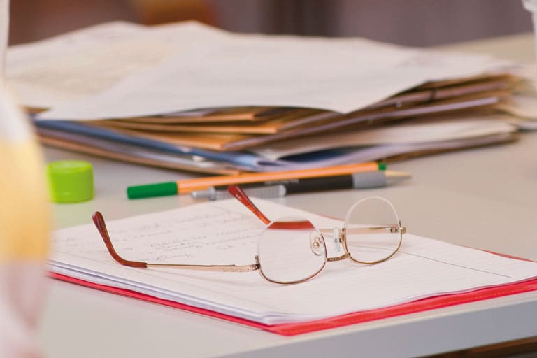 Brille liegt auf Papieren auf dem Schreibtisch, Foto: PIZKB