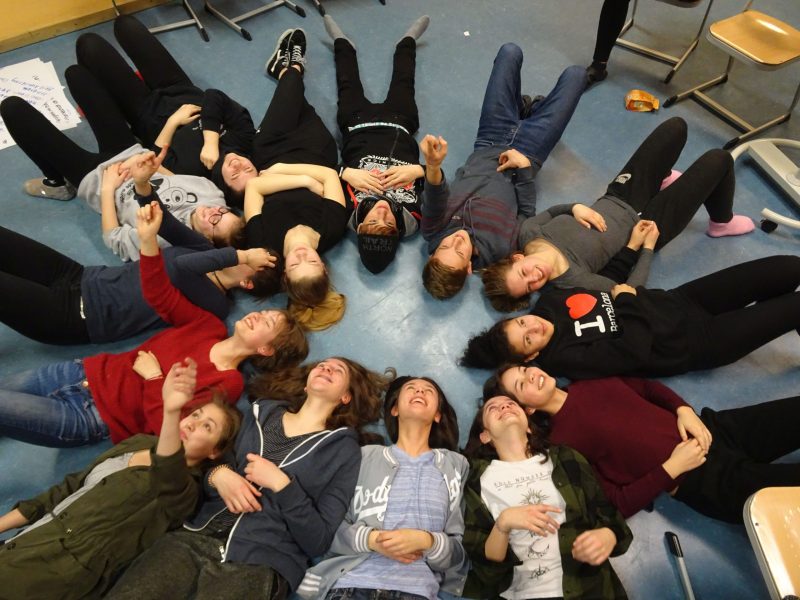 Gruppe von Schüler*innen im Kreis liegend