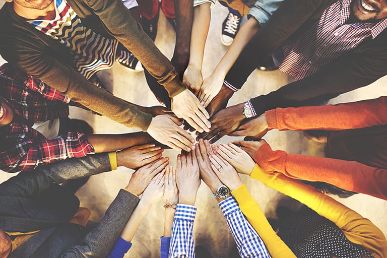 Viele Hände liegen in der Mitte des Bildes übereinander, Foto: Shutterstock, Rawpixel.com